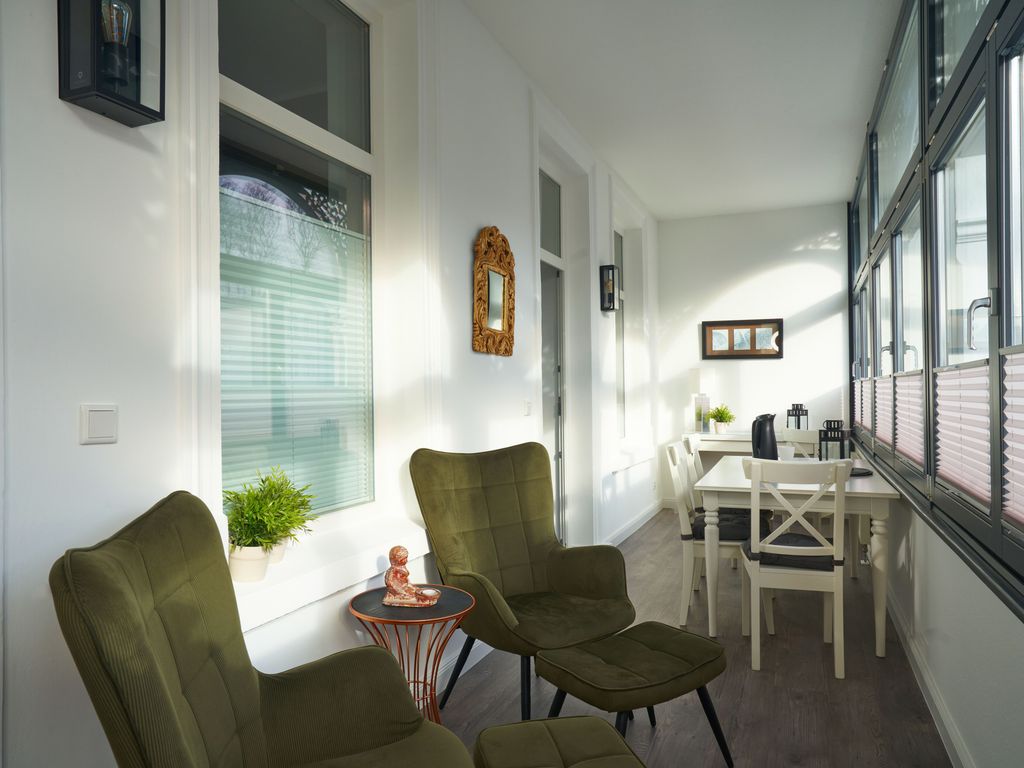 Der helle Wintergarten mit Essbereich und Lounge-Ecke