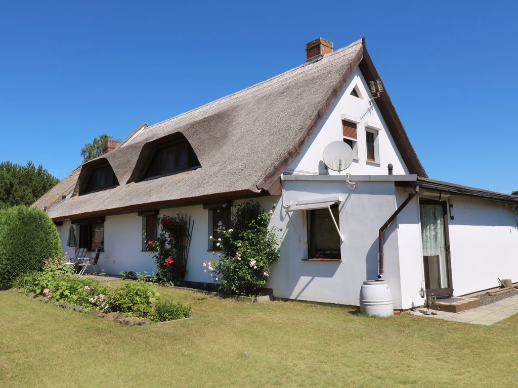 3. Seitliche Hausansicht###br###Die Ferienwohnung Am Peenestrom im Ostseebad Karlshagen auf der Insel Usedom befindet sich in einem reetgedeckten Haus mit seitlicher Rasenfläche und angrenzender Bebauung.