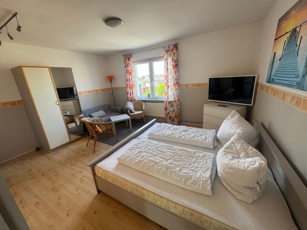 Großzügiger Wohn- und Schlafbereich der Ferienwohnung Seewind in zentraler Lage von Karlshagen auf der Insel Usedom mit Doppelbett, TV und gemütlicher Sitzecke.
