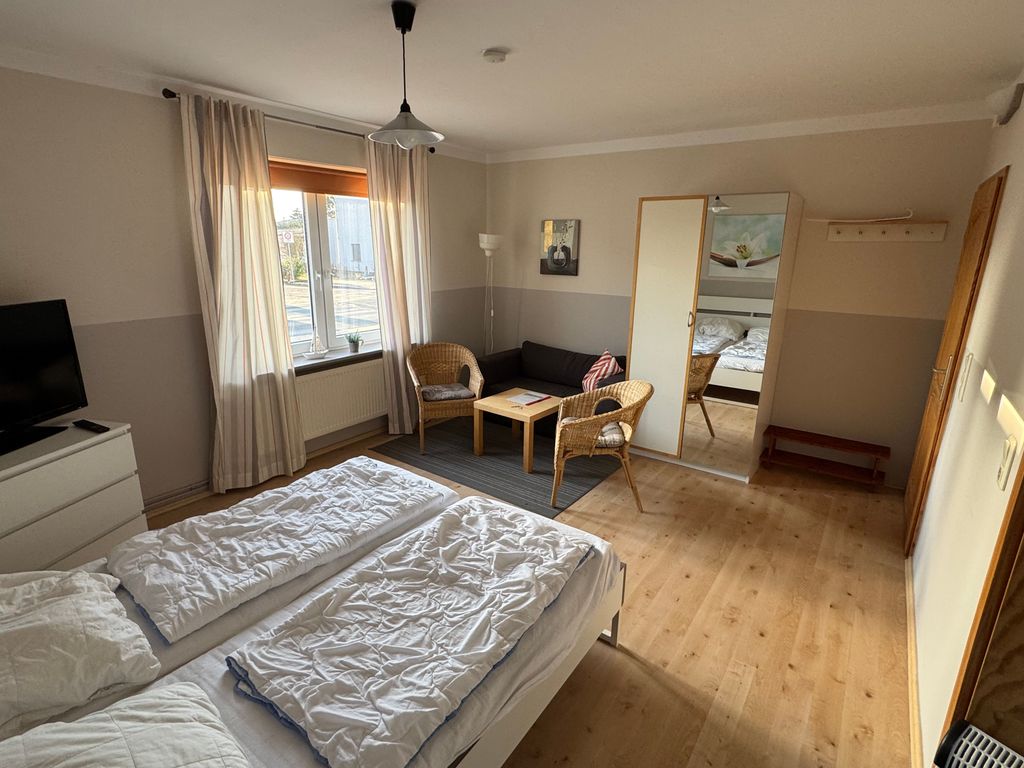 Großzügiger Wohn- und Schlafbereich der Ferienwohnung Seewind in zentraler Lage von Karlshagen auf der Insel Usedom mit Doppelbett, TV und gemütlicher Sitzecke.