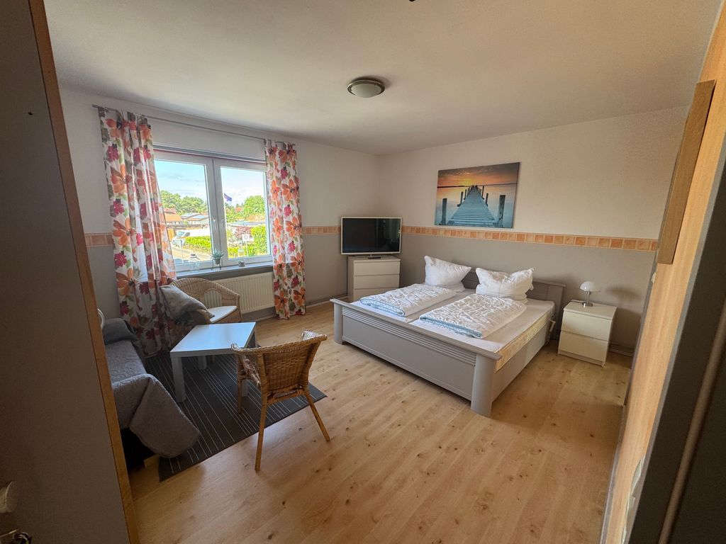 Großzügiger Wohn- und Schlafbereich der Ferienwohnung Seewind in zentraler Lage von Karlshagen auf der Insel Usedom mit Doppelbett, TV und gemütlicher Sitzecke.