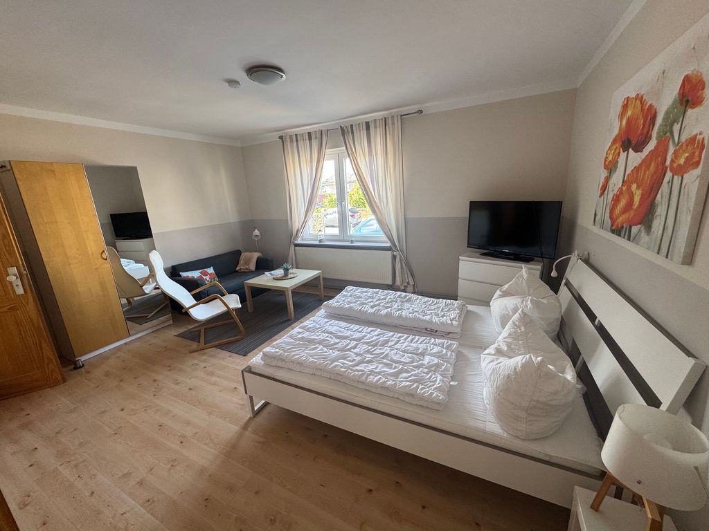 Großzügiger Wohn- und Schlafbereich der Ferienwohnung Seewind in zentraler Lage von Karlshagen auf der Insel Usedom mit Doppelbett, TV und gemütlicher Sitzecke.
