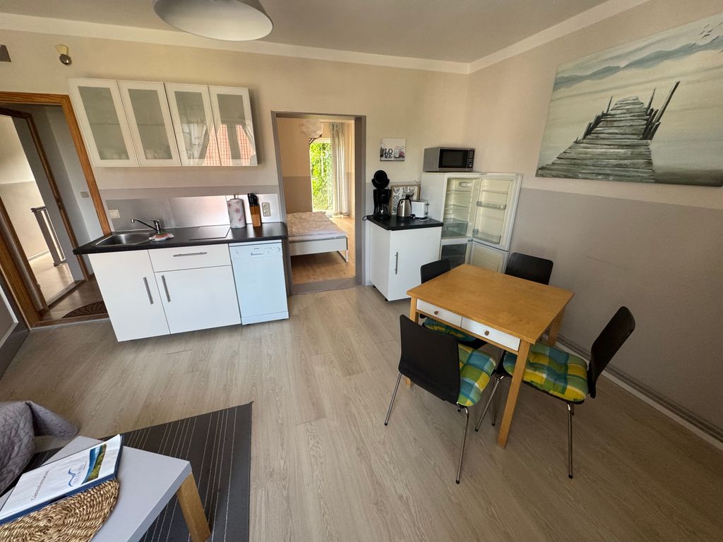 Heller Wohn- und Essbereich der Ferienwohnung Seewind in zentraler Lage von Karlshagen auf der Insel Usedom mit offener Küchenzeile, Essplatz und gemütlicher Sitzecke.