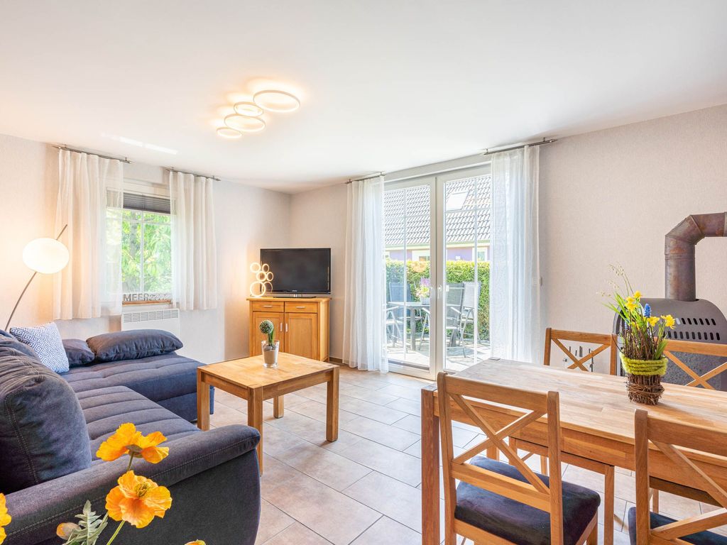Das Ferienhaus Mimi im Ostseebad Karlshagen auf der Insel Usedom zeigt den Wohn- und Essbereich mit Esstisch und großen Fenstern für viel Tageslicht.
