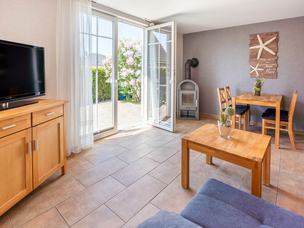 Das Ferienhaus Mimi im Ostseebad Karlshagen auf der Insel Usedom zeigt den Essbereich mit Esstisch und angrenzendem Kaminofen sowie den Terrassenzugang.
