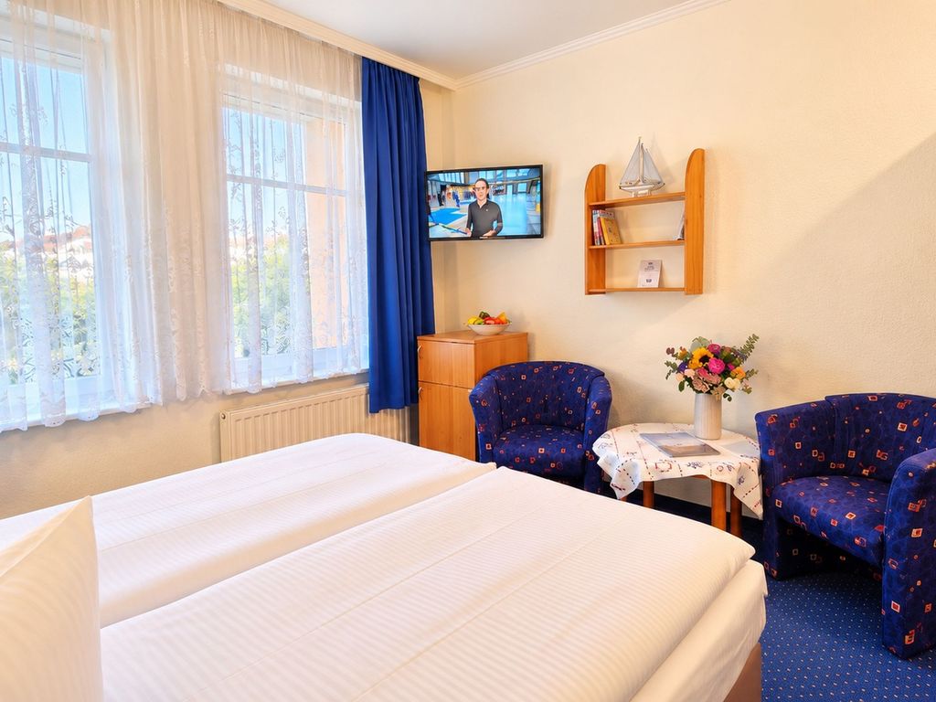 Doppelzimmer mit Doppelbett, Sitzgelegenheit und kleinem Kühlschrank