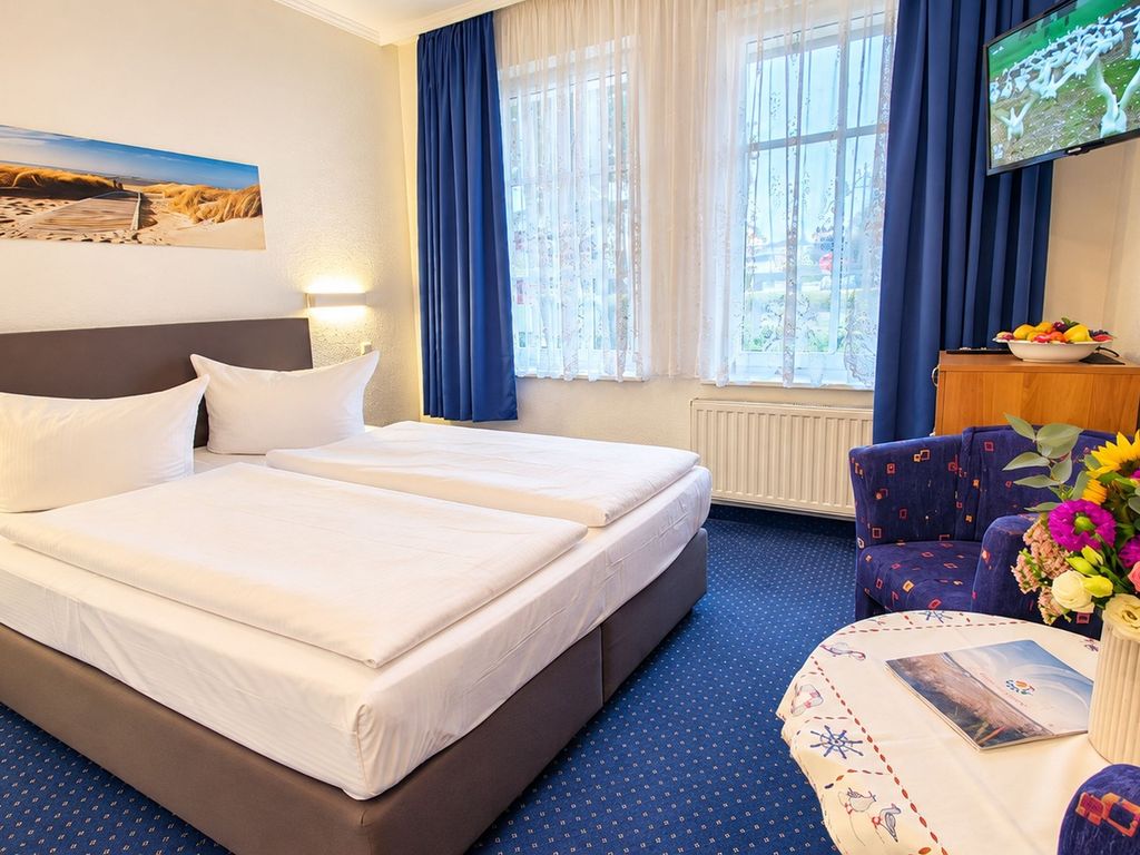 Doppelzimmer mit Doppelbett, Sitzgelegenheit und kleinem Kühlschrank