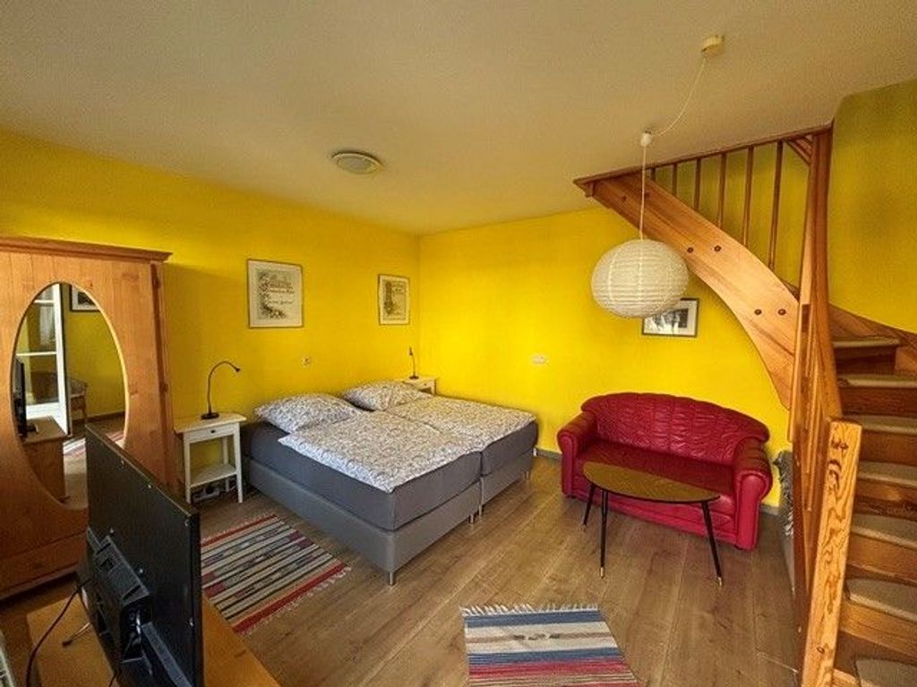 kombiniertes Wohnzimmer-Schlafzimmer mit Doppelbett und Schlafcouch
(Treppe führt in die Küche der Ferienwohnung)