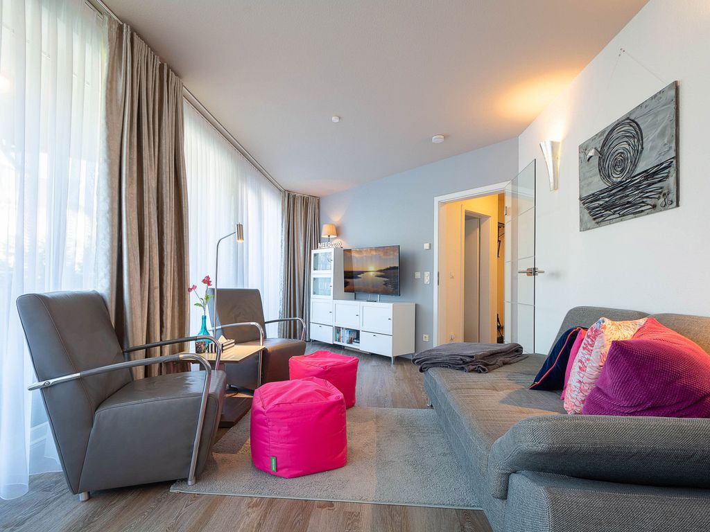 Das modern eingerichtete Wohnzimmer mit gemütlicher Couchgarnitur und Zugang zur möblierten Terrasse