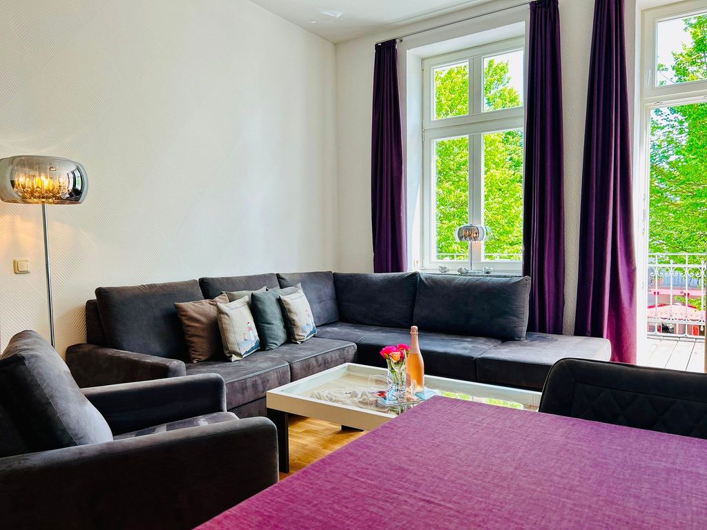 Das Wohnzimmer mit gemütlicher Sitzgarnitur und Zugang zum Balkon