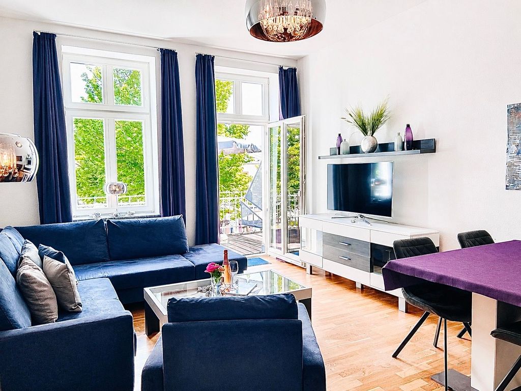 Der Wohnbereich mit gemütlicher Couchgarnitur, Flachbild-TV und Zugang zum möblierten Balkon