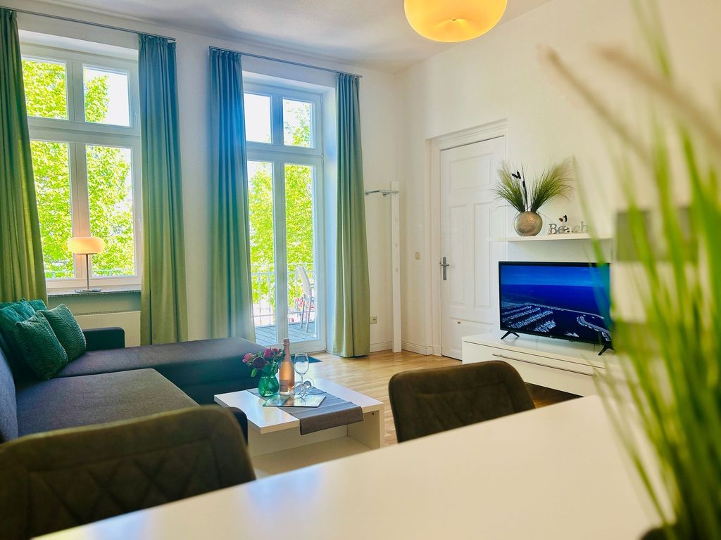 Das Wohnzimmer mit gemütlicher Couchgarnitur und Zugang zum möblierten Balkon