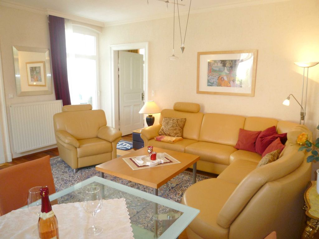 Wohnzimmer mit hochwertiger Ledergarnitur, besonderes Ambiente dank schöner Original-Holzböden, Kassettentüren und höherer Räume