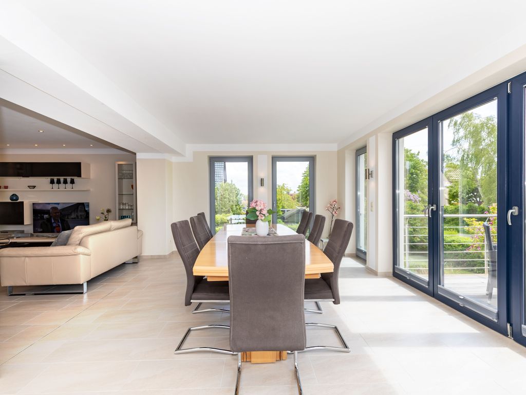 Das helle offene Wohnzimmer mit Sitzecke und Wintergarten mit einem großen Esstisch