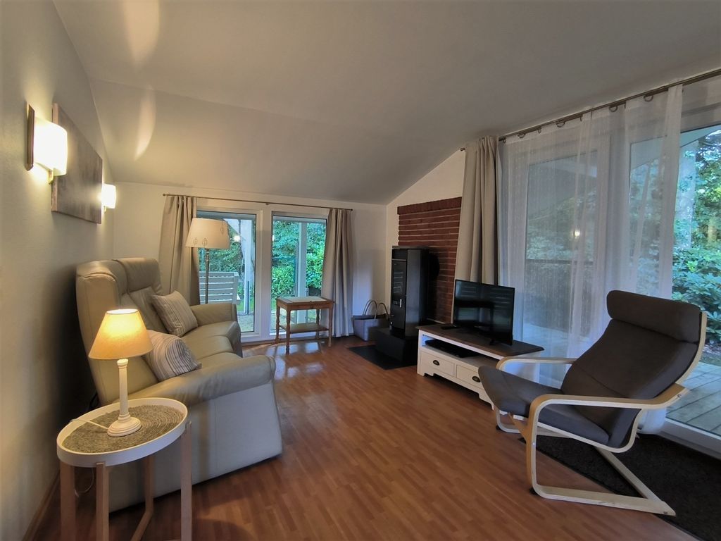 Wohnzimmer mit Sofa, Sessel, TV und Kamin