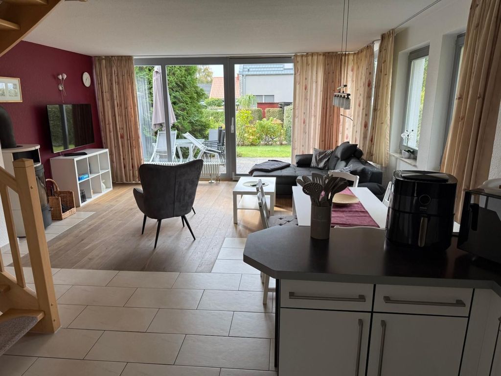 Gemütliches Wohnzimmer mit Kamin, großen Fenstern und viel Tageslicht für entspannte Abende.