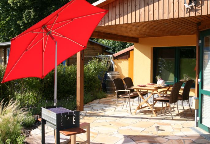 Teilüberdachte Terrasse mit Eßbereich draußen.