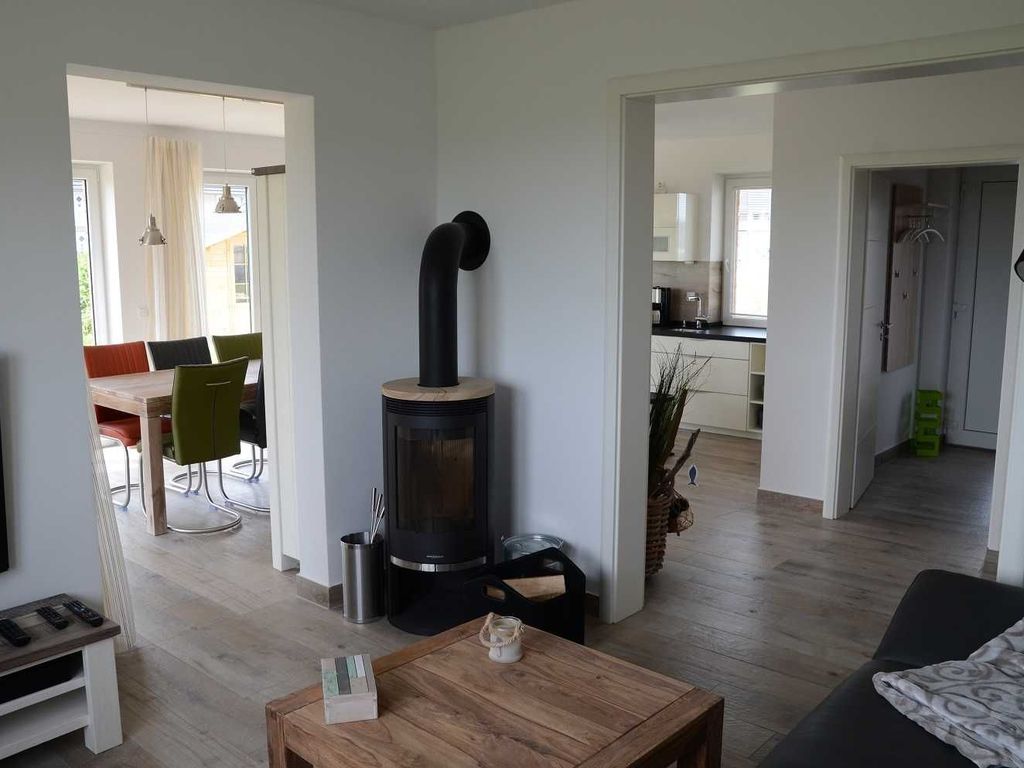 Das Ferienhaus Kormoran im Ostseebad Karlshagen auf der Insel Usedom zeigt einen hellen Essbereich mit Esstisch, Sitzplätzen und Kamin.