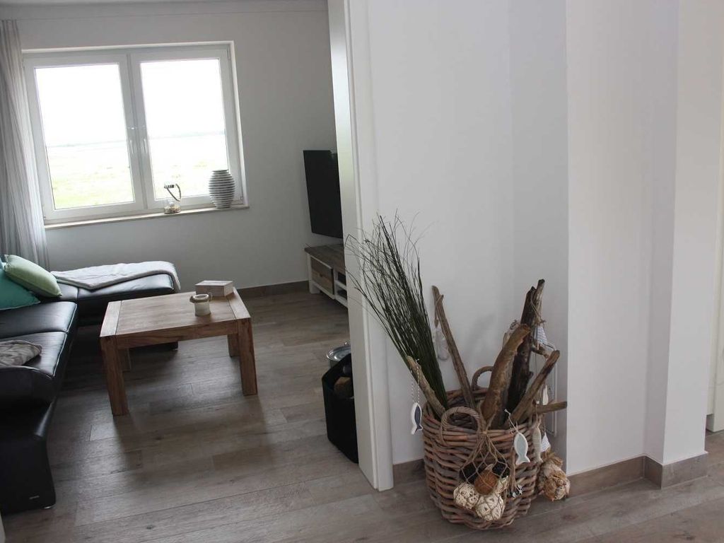 Das Ferienhaus Kormoran im Ostseebad Karlshagen auf der Insel Usedom zeigt einen gemütlichen Wohnbereich mit Sitzgruppe, Couchtisch und großen Fenstern.