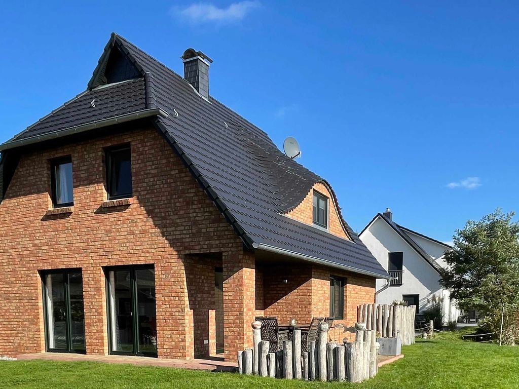 Das Ferienhaus Kormoran im Ostseebad Karlshagen auf der Insel Usedom zeigt sich in einer seitlichen Außenansicht mit Rasenfläche und Terrasse.