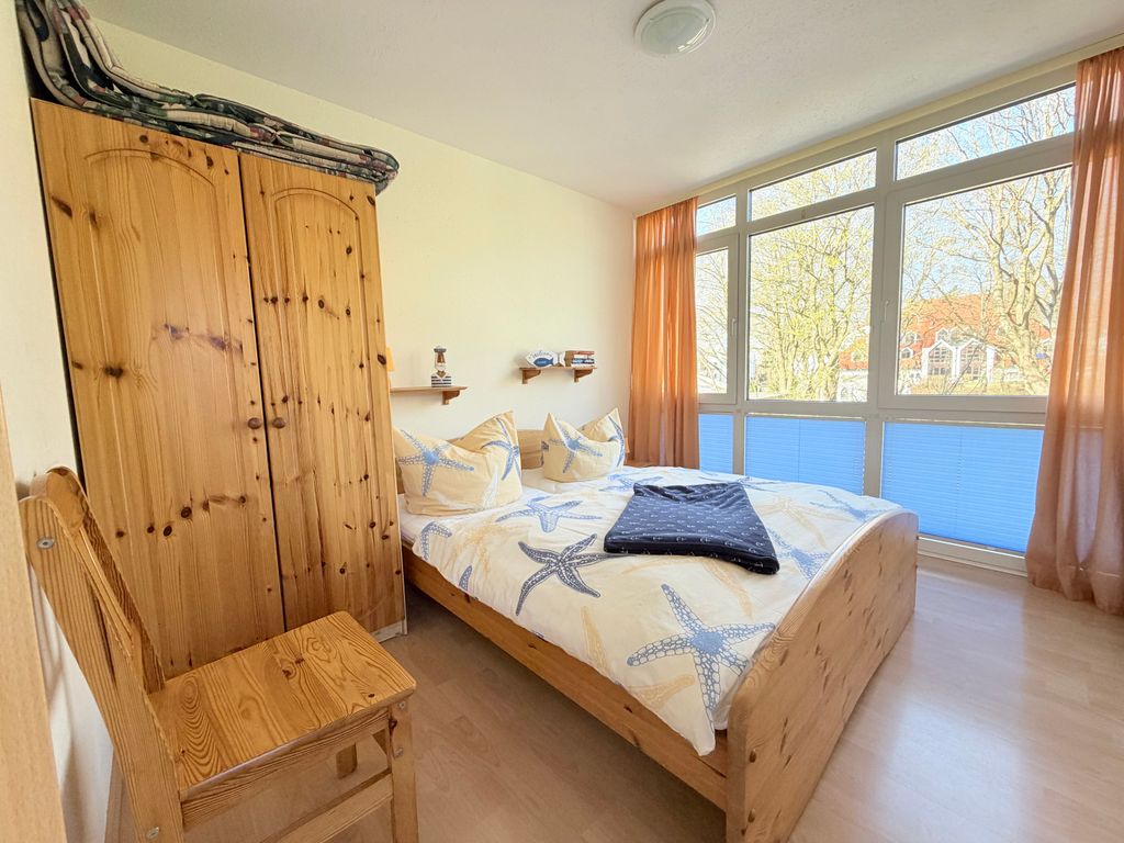 Schlafzimmer mit großem Doppelbett, einem Kleiderschrank und zusätzlichem Stuhl
