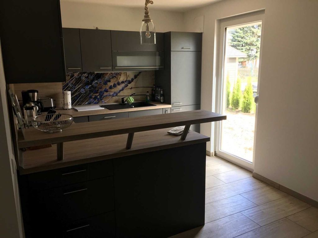 Offene Küche mit Küchengeräten - 
Das Ferienhaus Möwenkoje im Ostseebad Karlshagen auf der Insel Usedom zeigt die offene Küche mit Kochfeld, Backofen, Spülbecken und Kühlschrank.