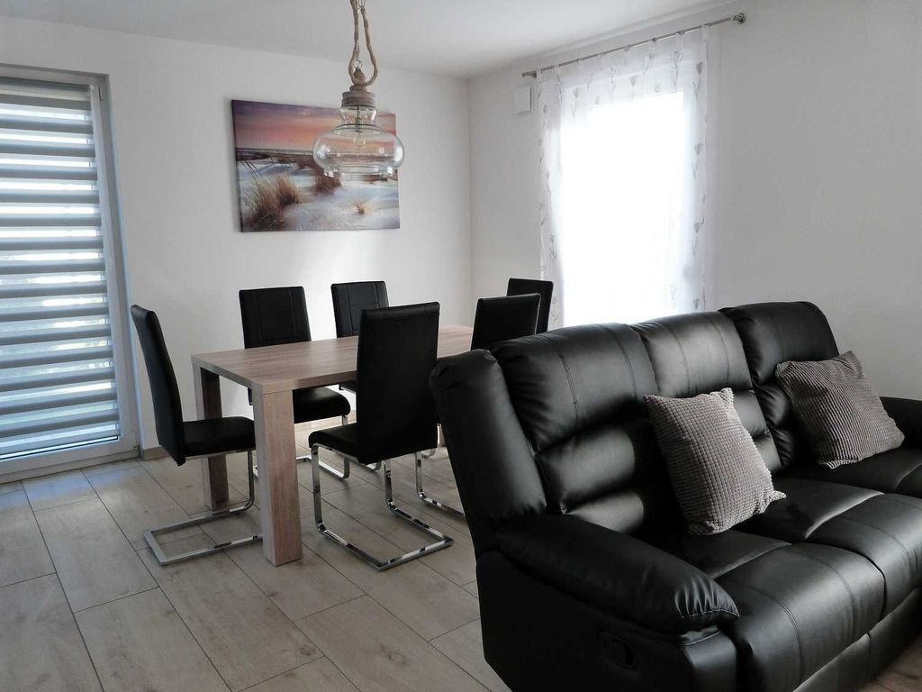 Wohnzimmer mit Fenstern - 
Das Ferienhaus Möwenkoje im Ostseebad Karlshagen auf der Insel Usedom zeigt einen hellen Wohnbereich mit Ledersofa und großen Fenstern.