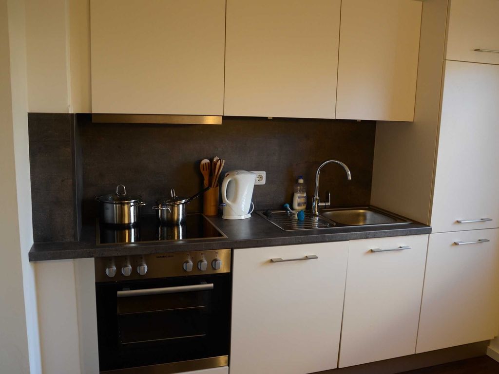Küche im Ferienhaus Hannahliese in Karlshagen auf der Insel Usedom mit Küchenzeile und Elektrogeräten - wie Herd, Backofen, Kühlschrank, Geschirrspüler, Mikrowelle und Kaffeemaschine.