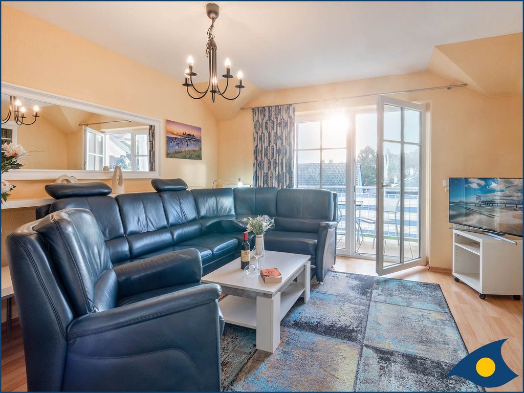 Wohnzimmer mit offener Küche und Zugang zum Balkon