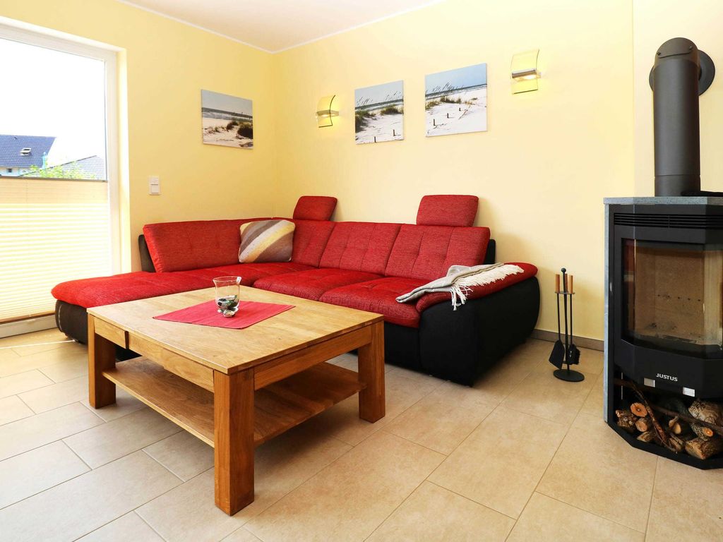 Gemütlicher Wohnbereich mit Kaminofen 
Das Ferienhaus Sinha im Ostseebad Karlshagen auf der Insel Usedom zeigt einen gemütlichen Wohnbereich mit roter Sitzgruppe, Couchtisch und Kaminofen.