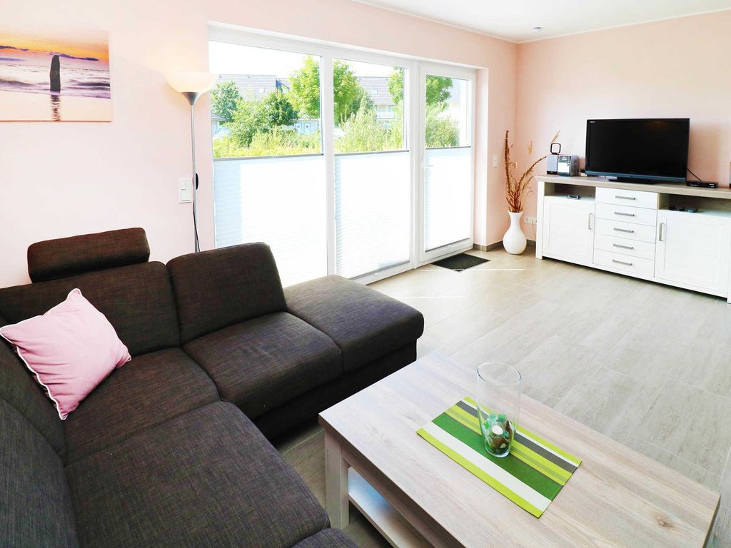 2. Wohnbereich mit Fernseher 
Das Ferienhaus Wis im Ostseebad Karlshagen auf der Insel Usedom zeigt einen gemütlichen Wohnbereich mit Eckcouch, Wohnzimmertische, Kommode und Fernseher.