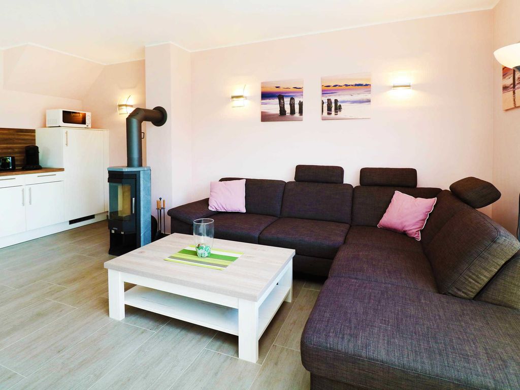 1. Heller Wohnbereich mit Kaminofen
Das Ferienhaus Wis im Ostseebad Karlshagen auf der Insel Usedom zeigt einen hellen Wohnbereich mit großer Eckcouch, Couchtisch, Kaminofen und offenem Küchenbereich.