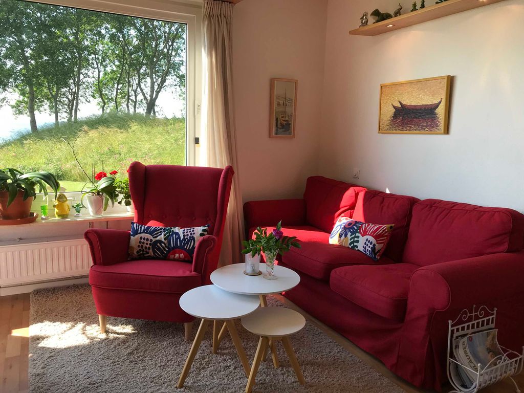 Wohnzimmer mit Meerblick, gemütlicher Couch und Sessel